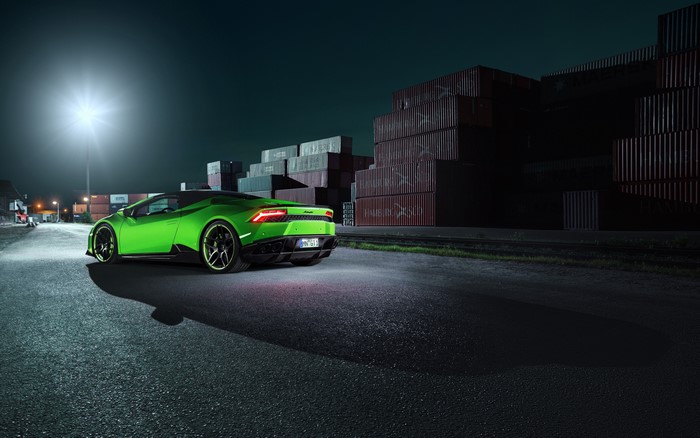 Green Lamborghini parked near shipping containers at night