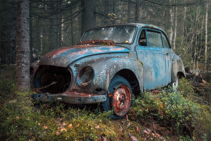 Abandoned blue car in a forest