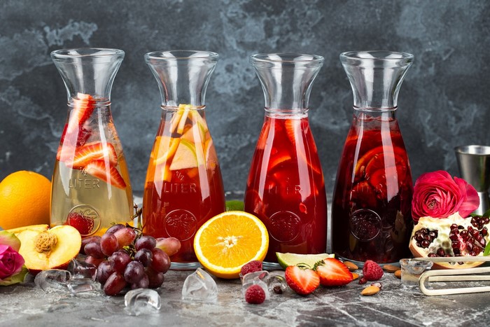 Four carafes of fruit-infused drinks with fresh fruit and ice