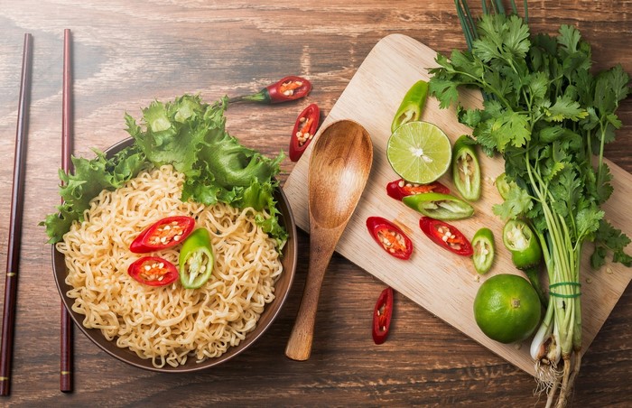 Noodles with chili peppers and lime on a wooden table