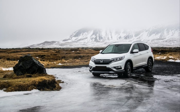 White Honda CR-V parked on icy ground with snowy mountains