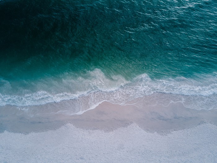 Aerial view of ocean waves crashing on a sandy beach