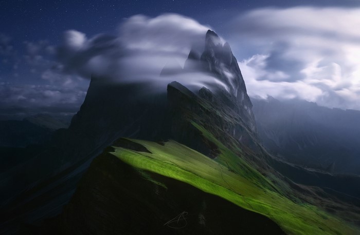 Mountains shrouded in clouds under a starry night sky