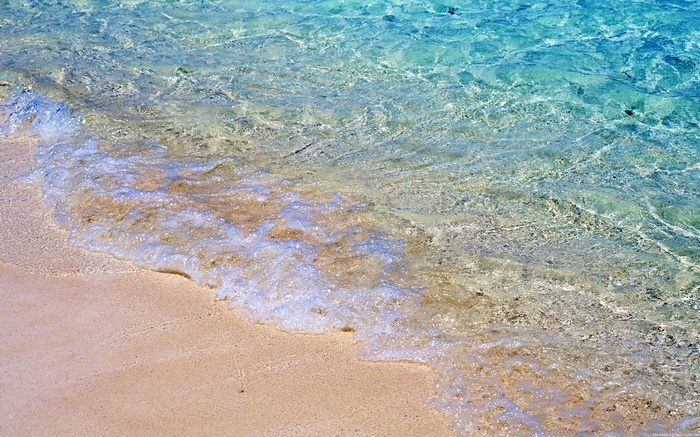 Clear turquoise water washes onto a sandy beach