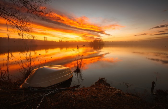 Boat on a lake at sunset with orange sky