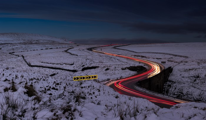 Light trails on a snowy road at dusk