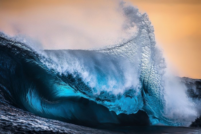 Crashing ocean wave with golden sky