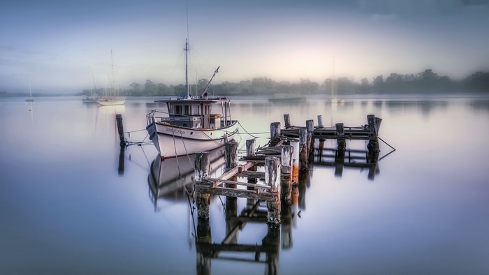 Boat docked at a weathered pier on a misty lake