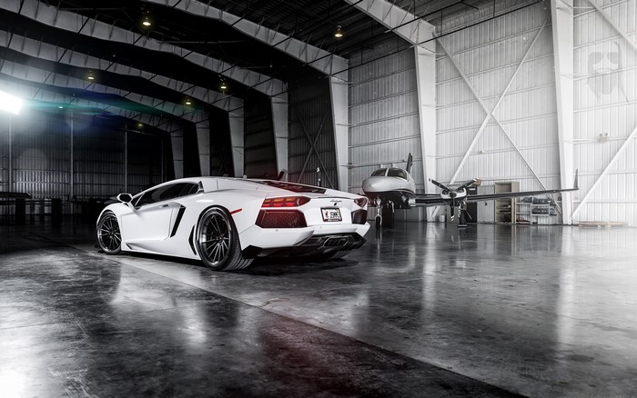 White Lamborghini Aventador in a hangar with a private jet