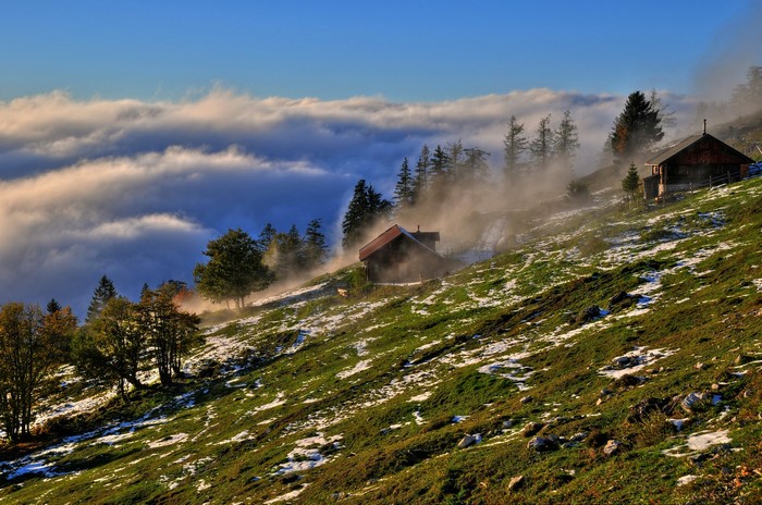 Mountain cabins above clouds with mist