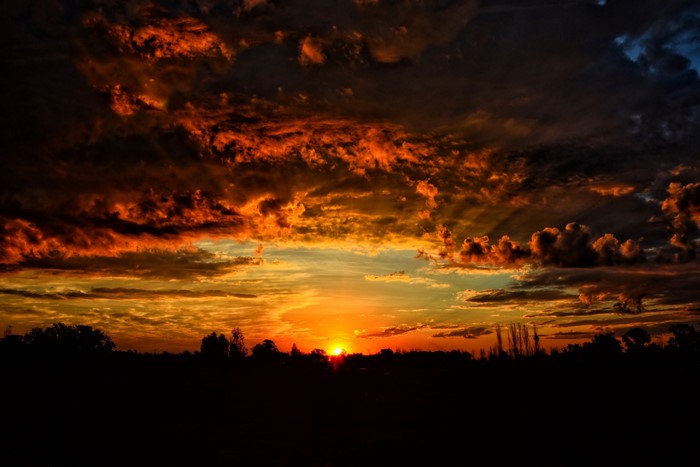 Dramatic sunset with fiery clouds over silhouetted landscape