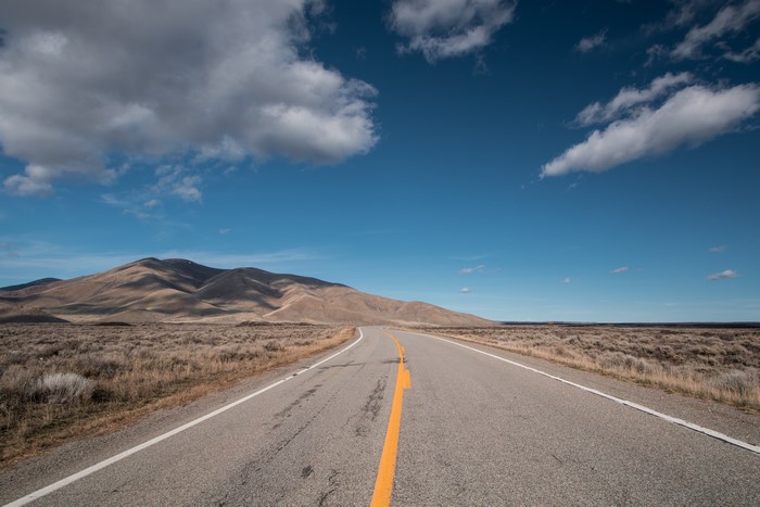 Road through Badlands landscape under cloudy sky