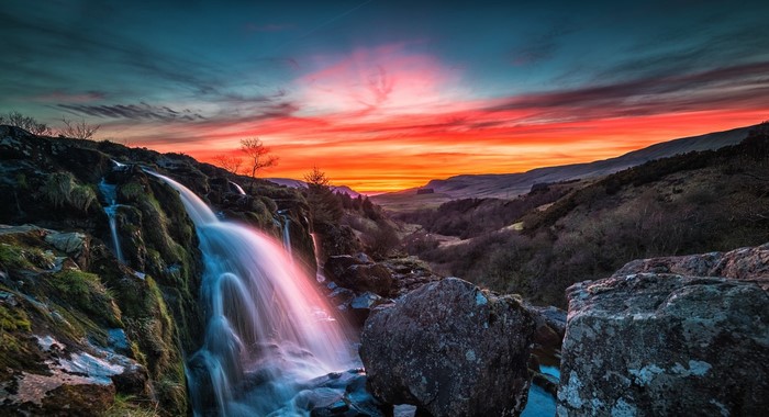 Waterfall flowing over rocks at sunset