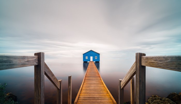 Blue house on a pier over calm water
