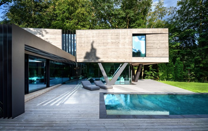 Modern concrete house with swimming pool and lounge chairs
