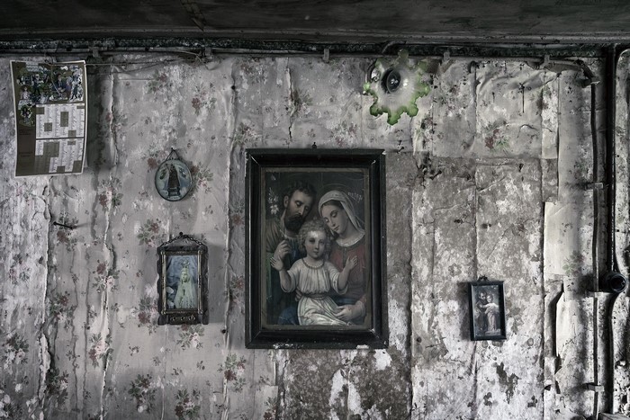 Religious paintings on a damaged floral wallpaper wall