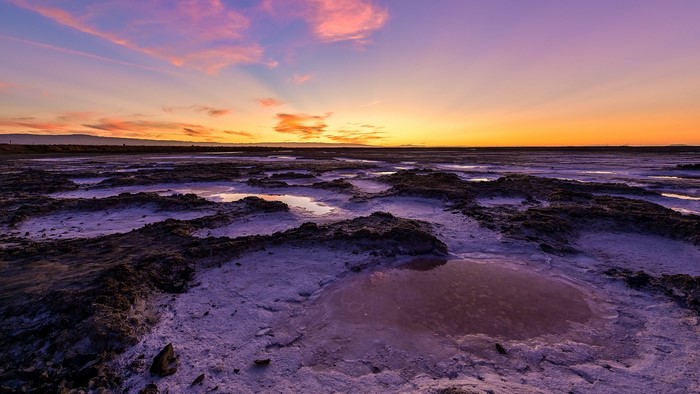 Sunset over a salt flat with pools of water