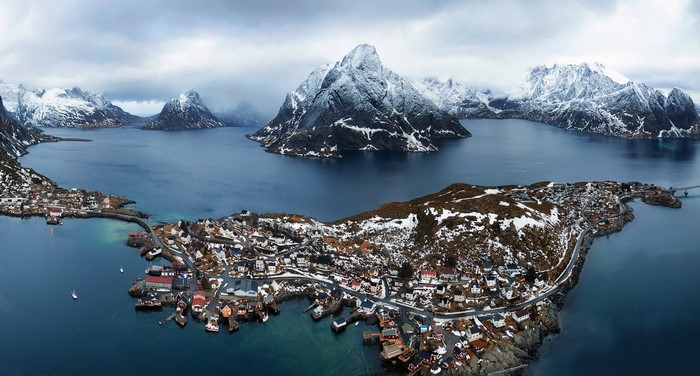 Aerial view of a Norwegian town nestled among snowy mountains and a bay