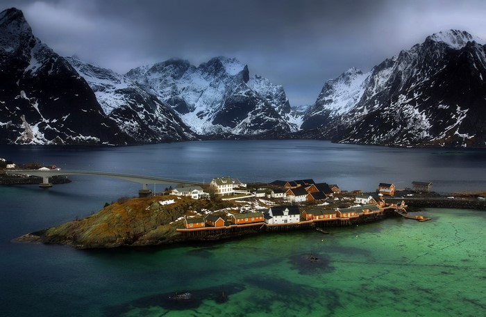 Village on island with snow-capped mountains and bridge in Norway