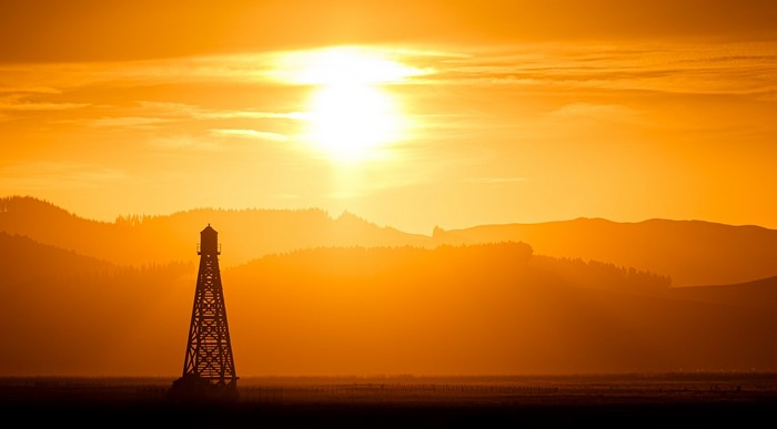 Silhouette of a water tower against a sunset