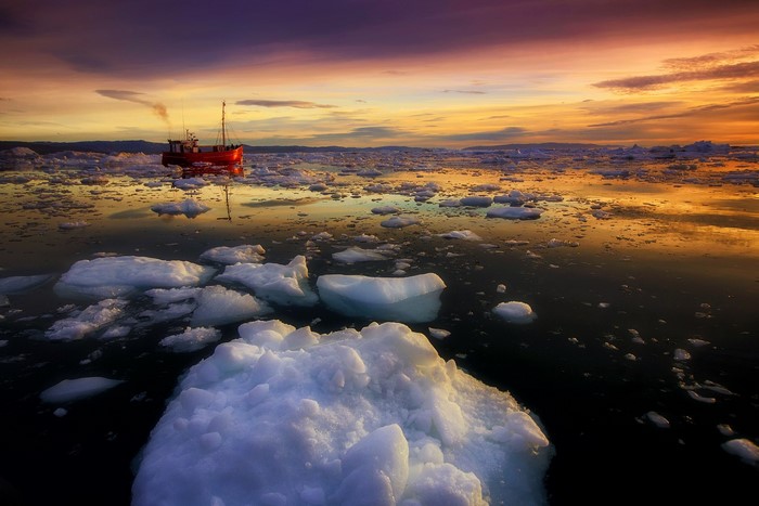 Red boat in ice floes at sunset