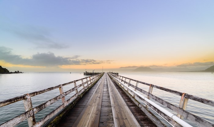 Wooden pier extending into the ocean at sunrise