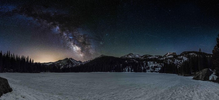 Milky Way over a snow-covered lake and mountains