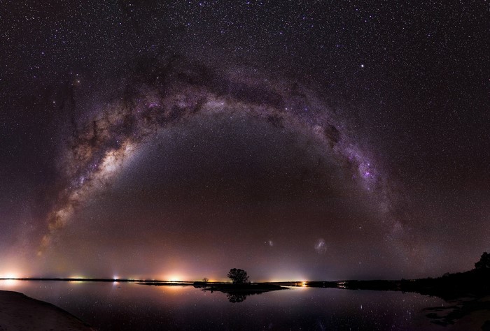 Milky Way galaxy arching over a reflective body of water at night