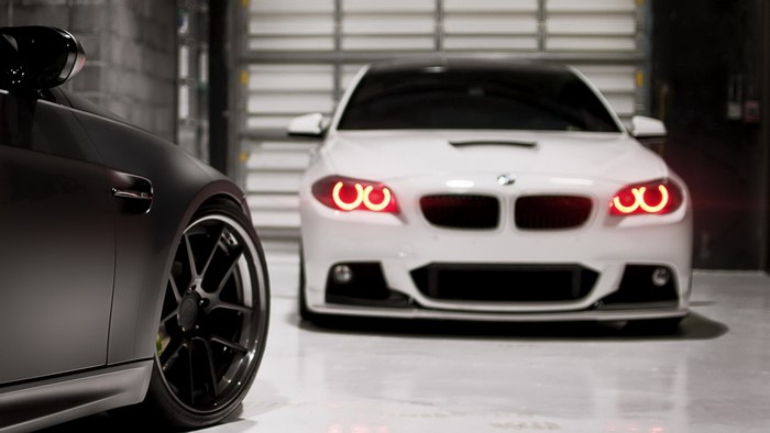 Two BMW cars in a garage, one black, one white