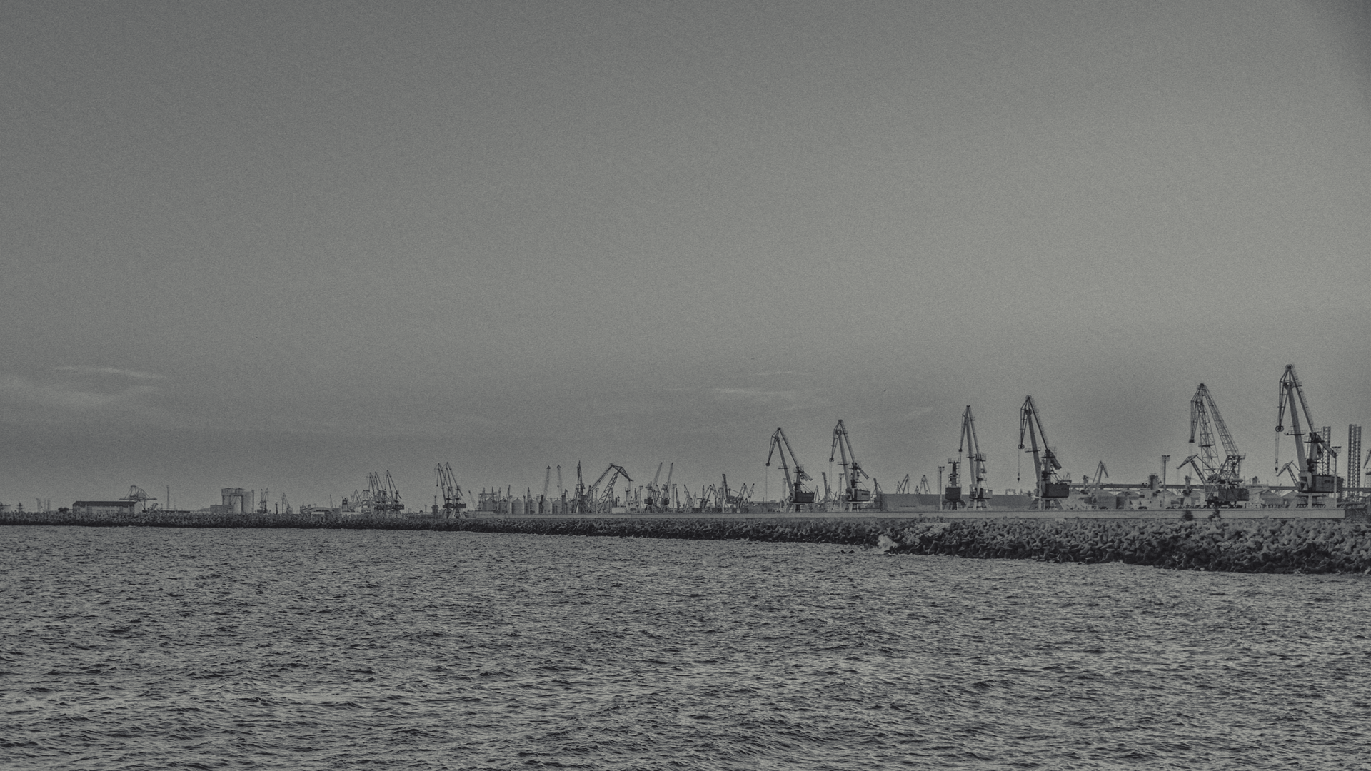 Port cranes on the coast with the sea in the foreground HD Wallpaper