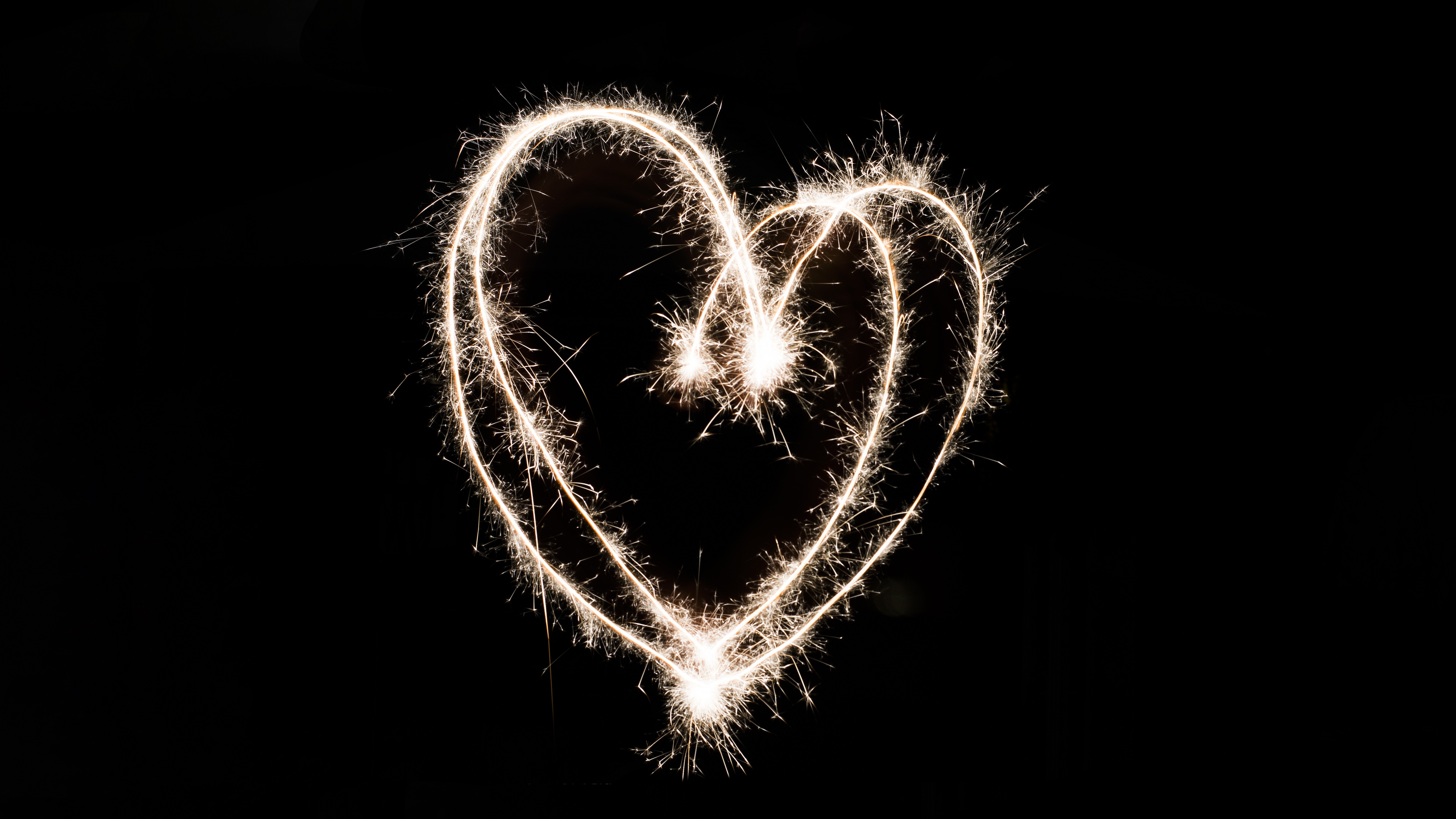 Heart shape made with sparklers on black background HD Wallpaper