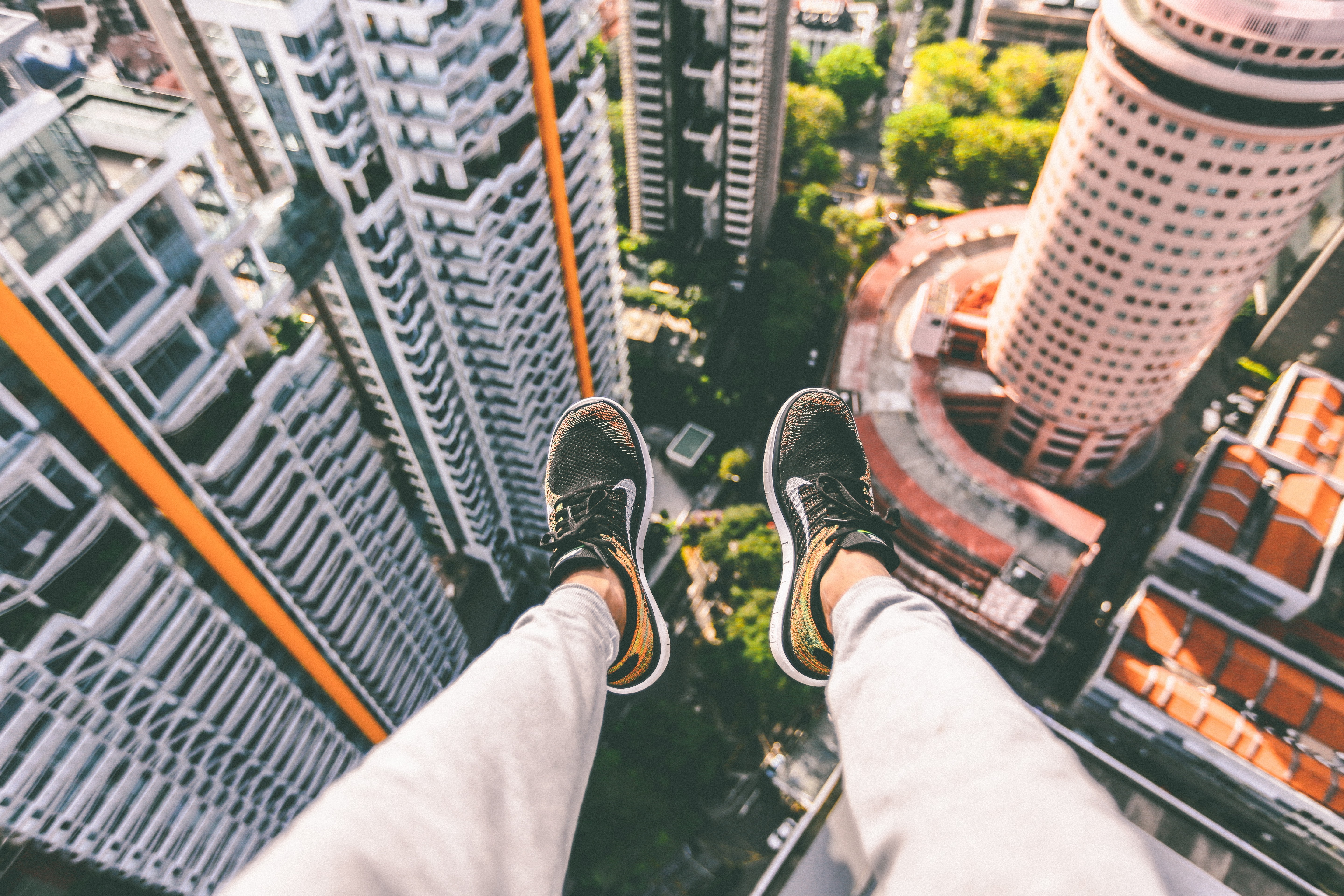 Person's feet dangling over a city skyline HD Wallpaper