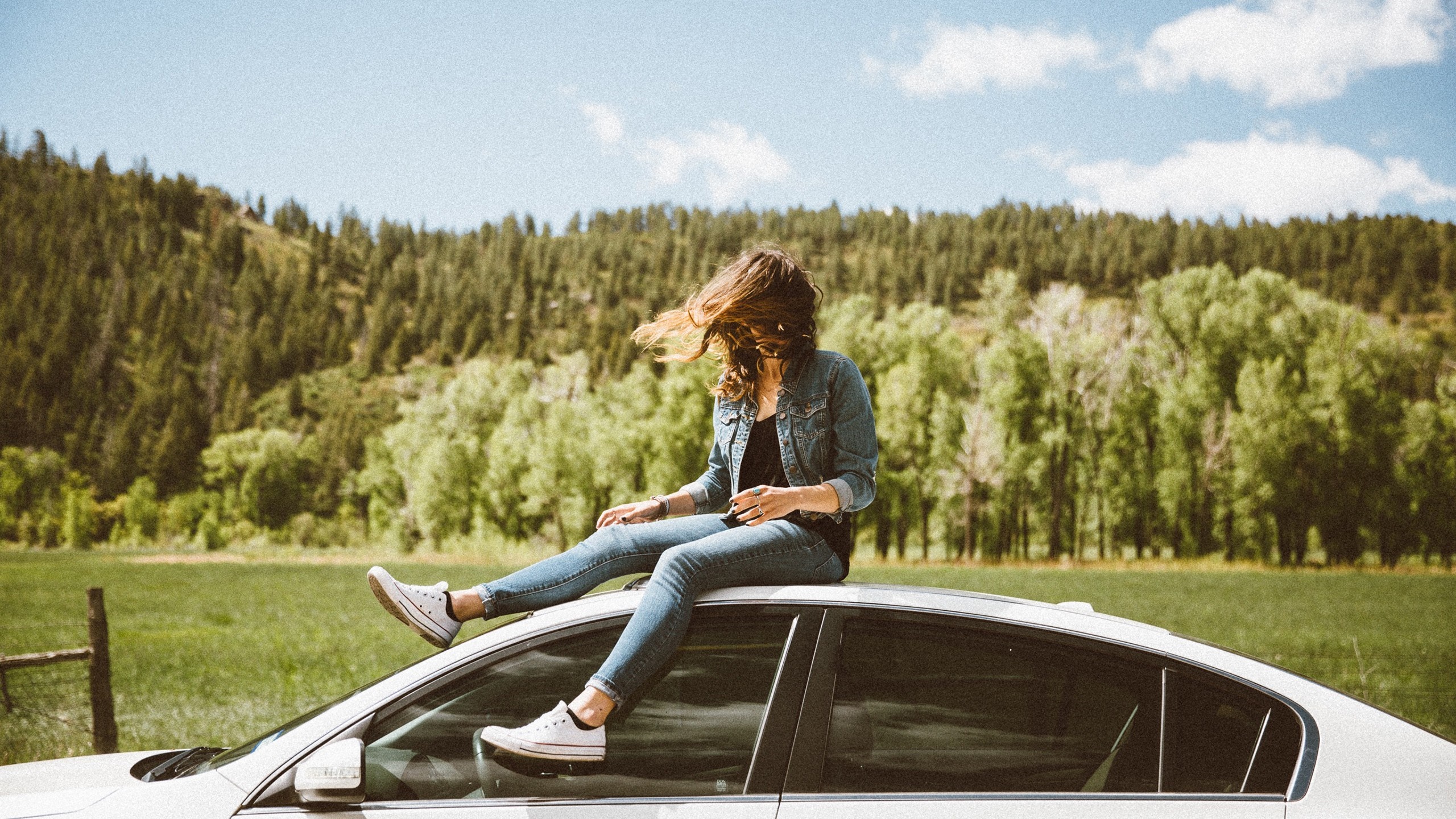 Woman sitting on car roof in a field HD Wallpaper