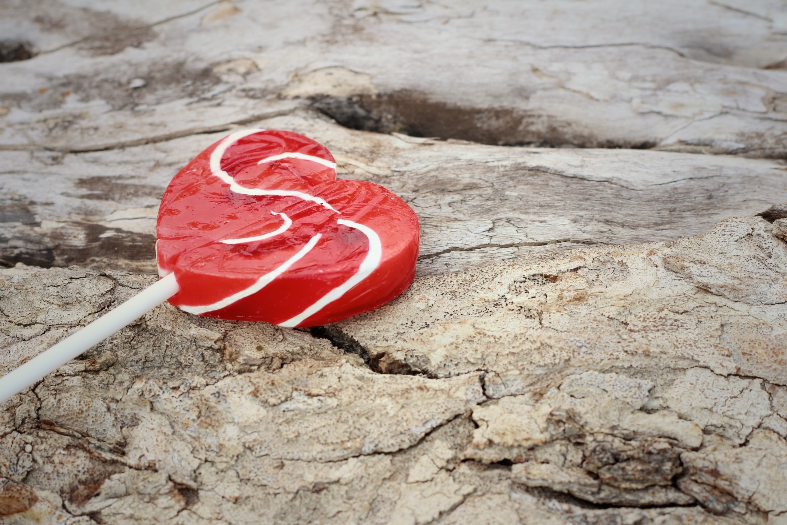 Red heart-shaped lollipop on textured wood HD Wallpaper
