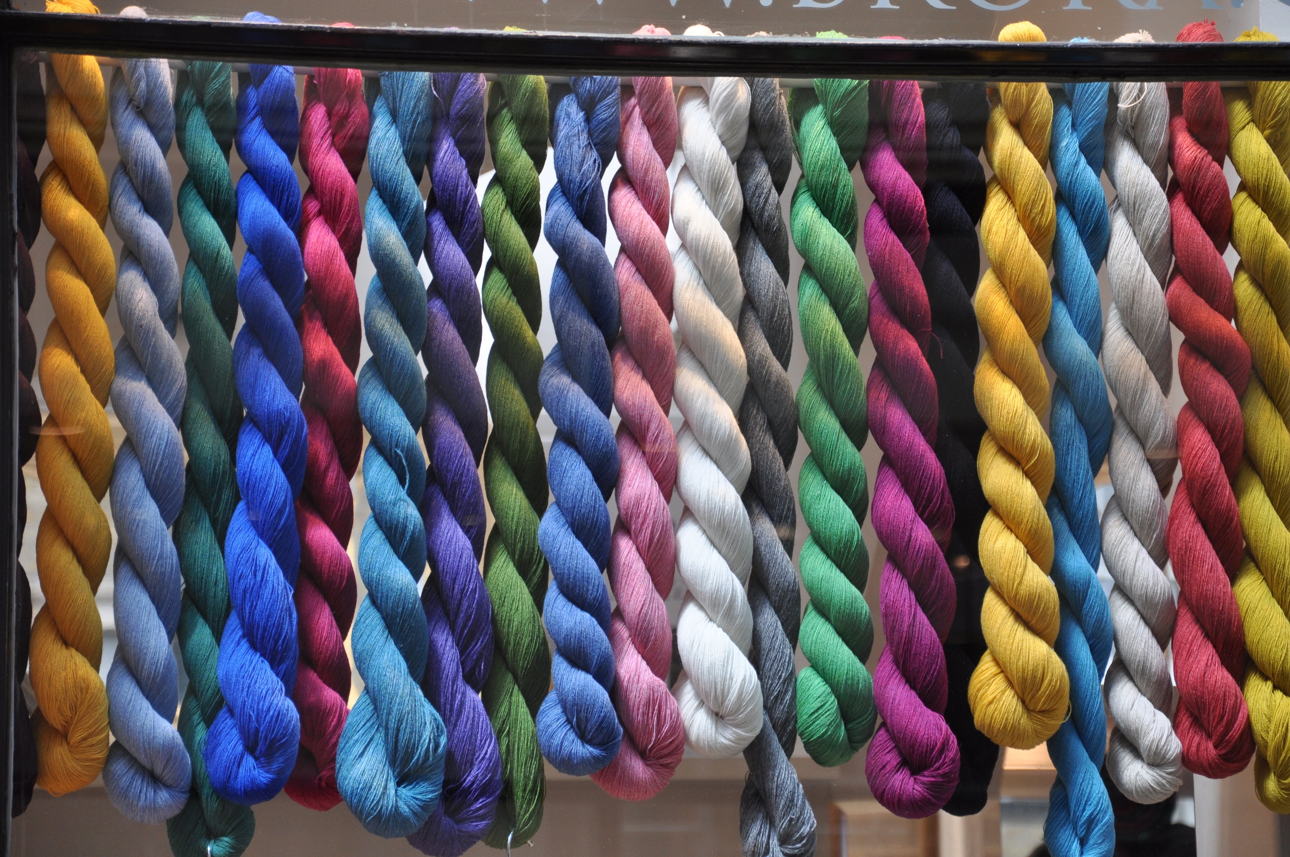 Colorful twisted yarn skeins hanging in a shop window HD Wallpaper