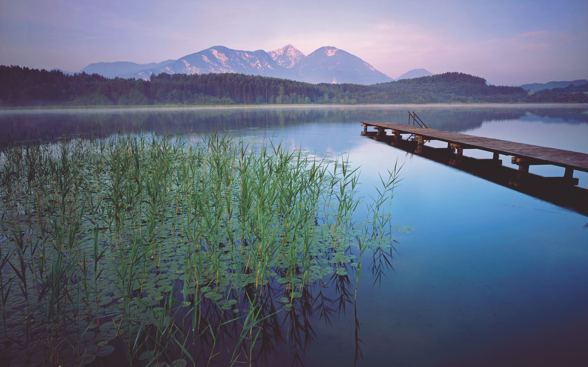 Wooden pier on a calm lake with mountains in the background HD Wallpaper