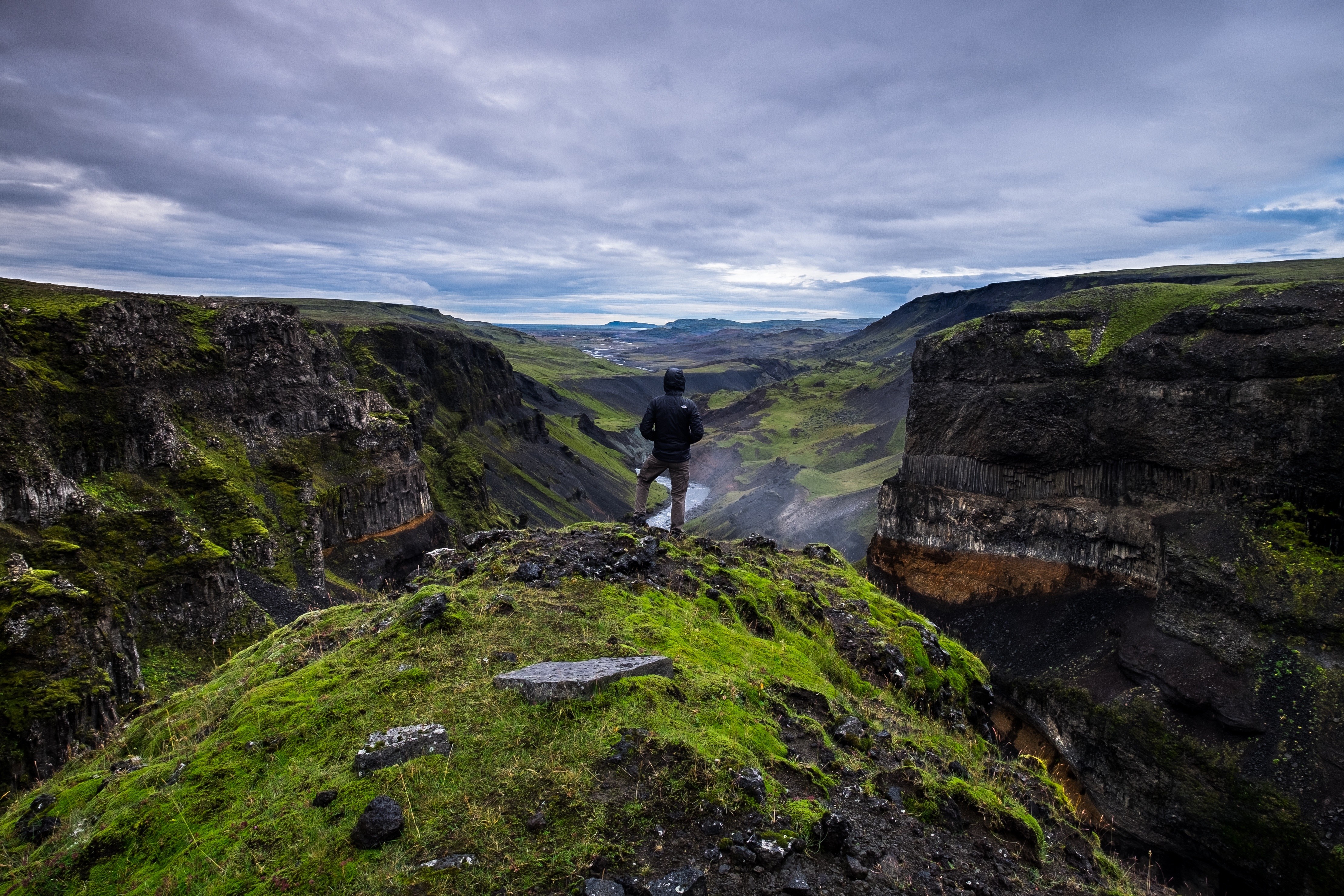 Man standing on cliff overlooking a vast canyon landscape HD Wallpaper