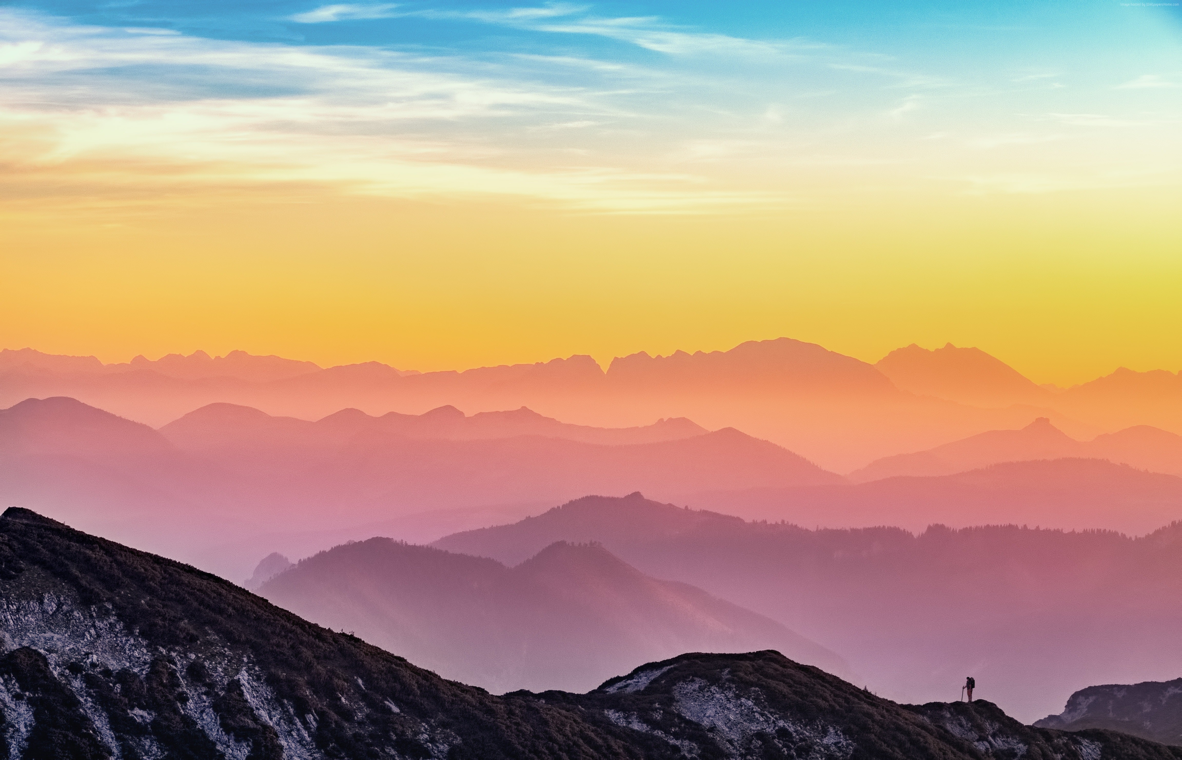 Mountain range at sunset with a lone hiker HD Wallpaper