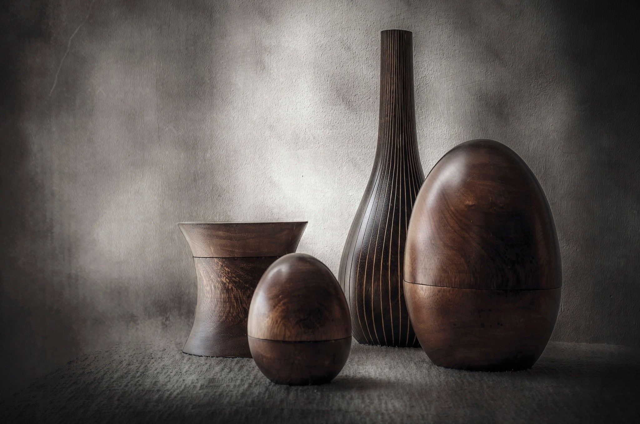 Wooden vases and egg-shaped sculptures on a textured background HD Wallpaper