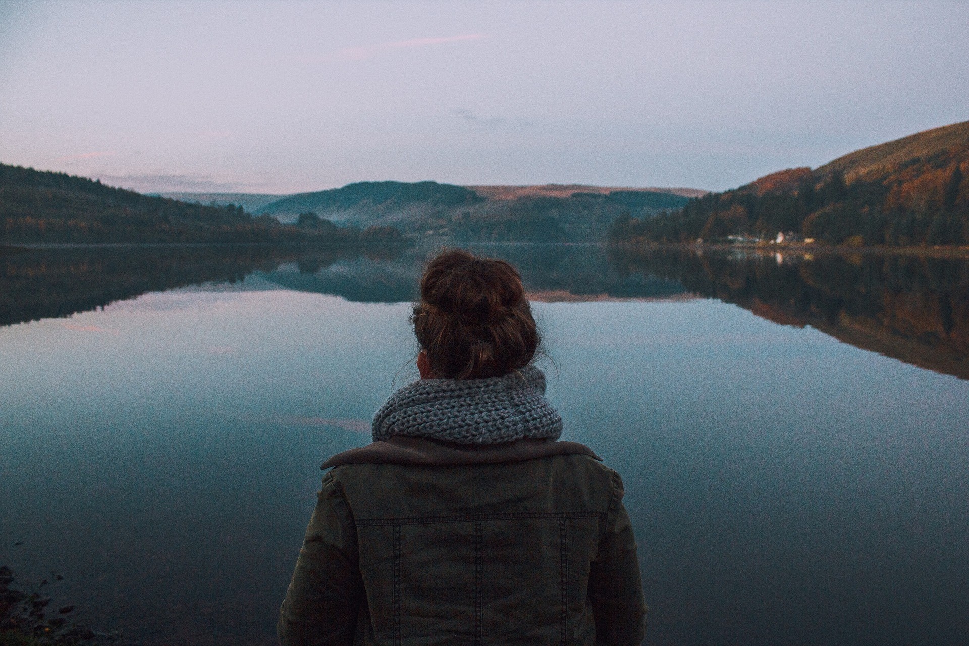 Woman with hair bun looking at a lake at dusk HD Wallpaper