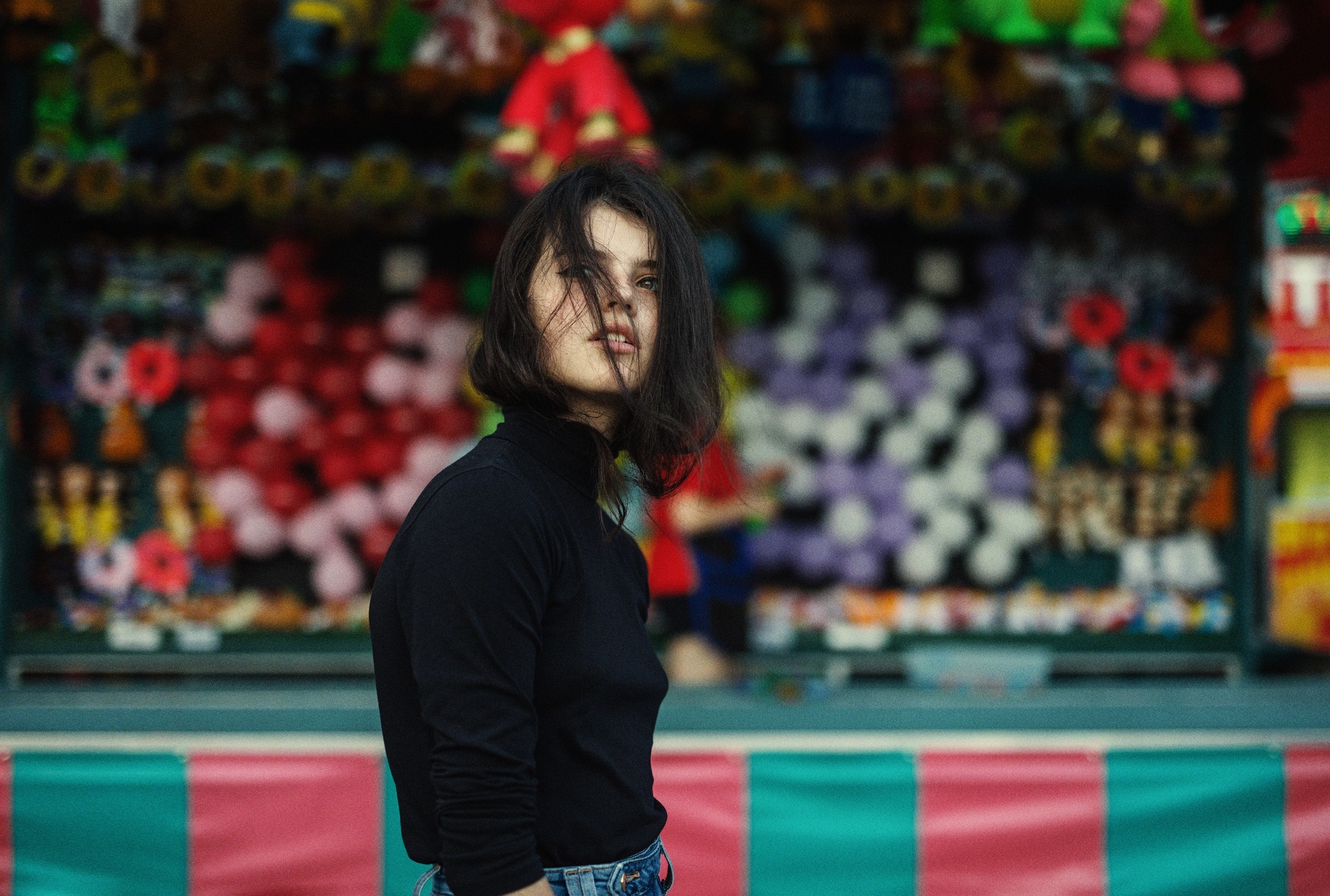 Woman in black turtleneck at a carnival game booth HD Wallpaper