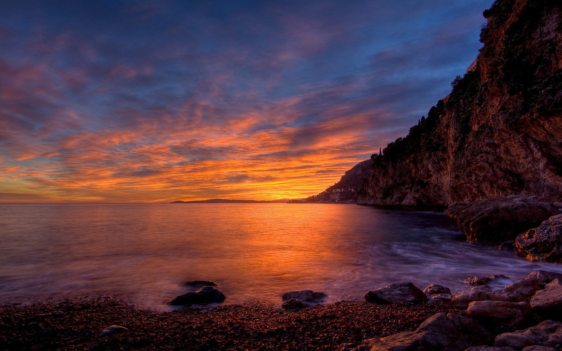 Sunset over a rocky coastline with colorful clouds HD Wallpaper