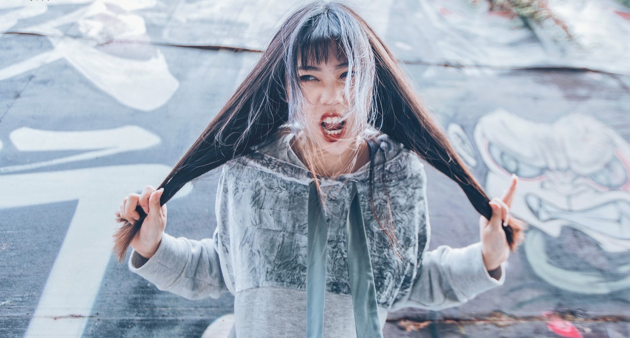 Woman with long hair pulling it in front of graffiti wall HD Wallpaper