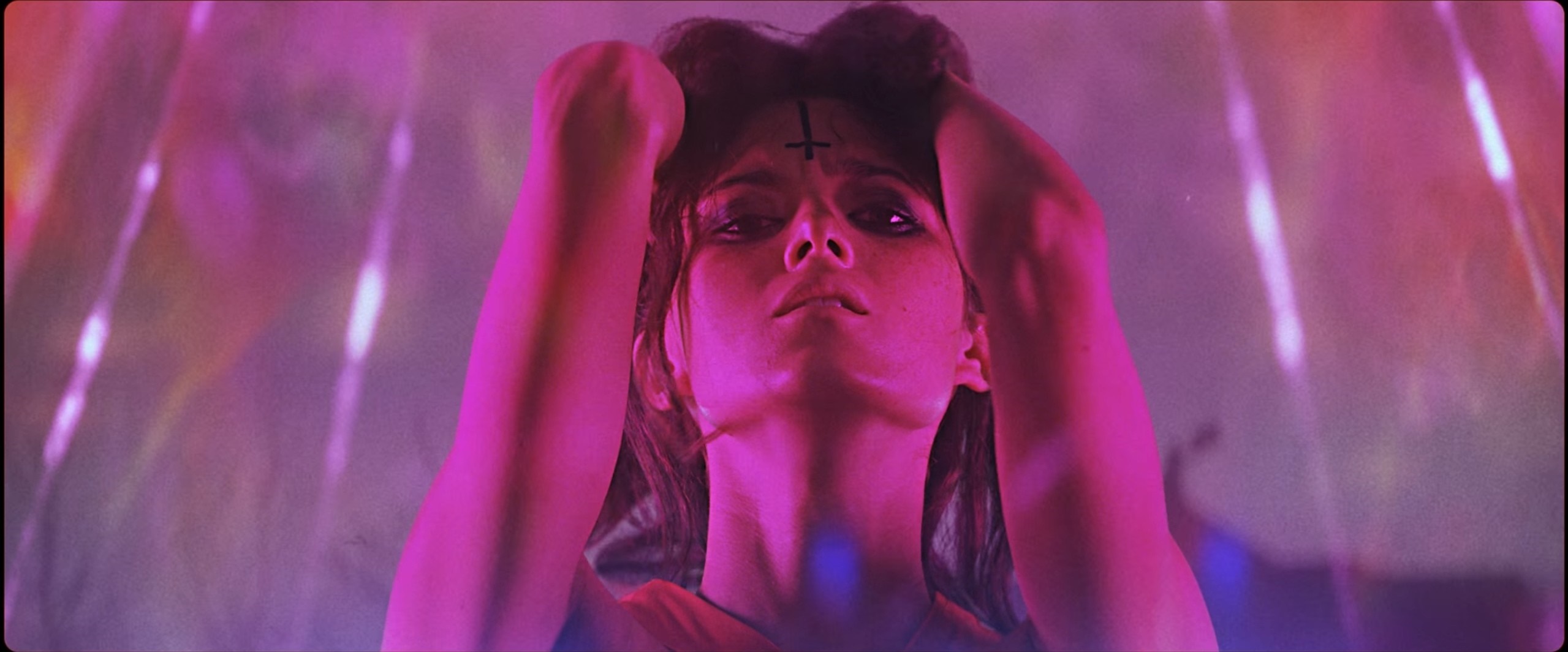 Woman with inverted cross on forehead in pink and purple lighting HD Wallpaper
