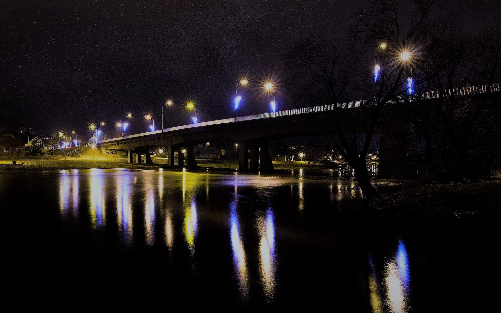 Bridge illuminated at night over a river with reflections HD Wallpaper