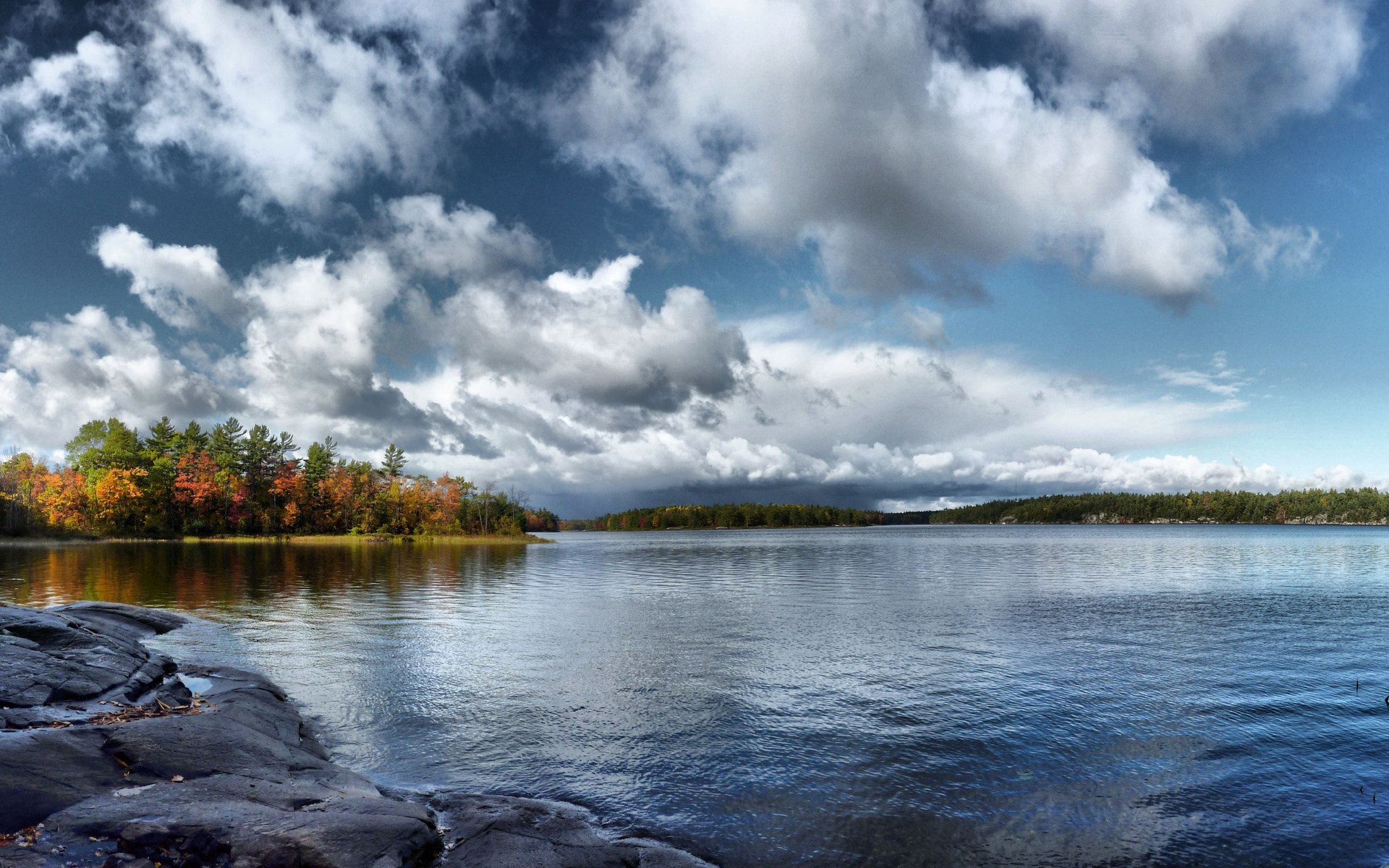Lake with autumn trees and rocky shore under cloudy sky HD Wallpaper