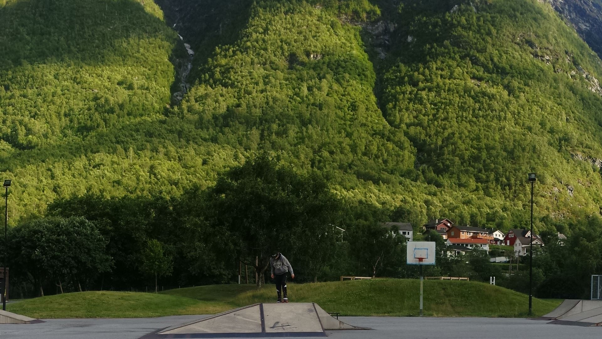 Person skateboarding in front of a mountain in Norway HD Wallpaper
