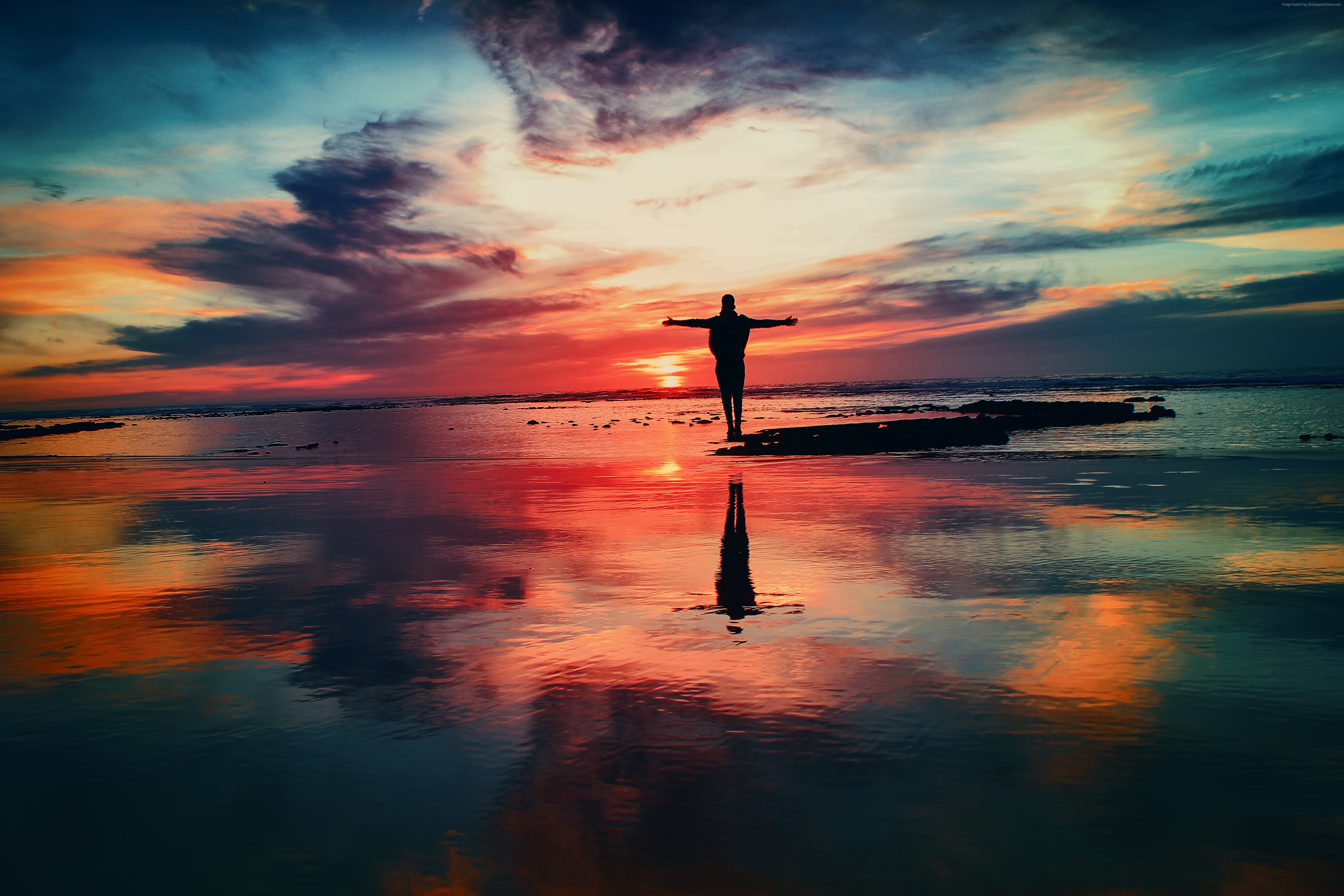 Man with arms outstretched at sunset over the ocean HD Wallpaper