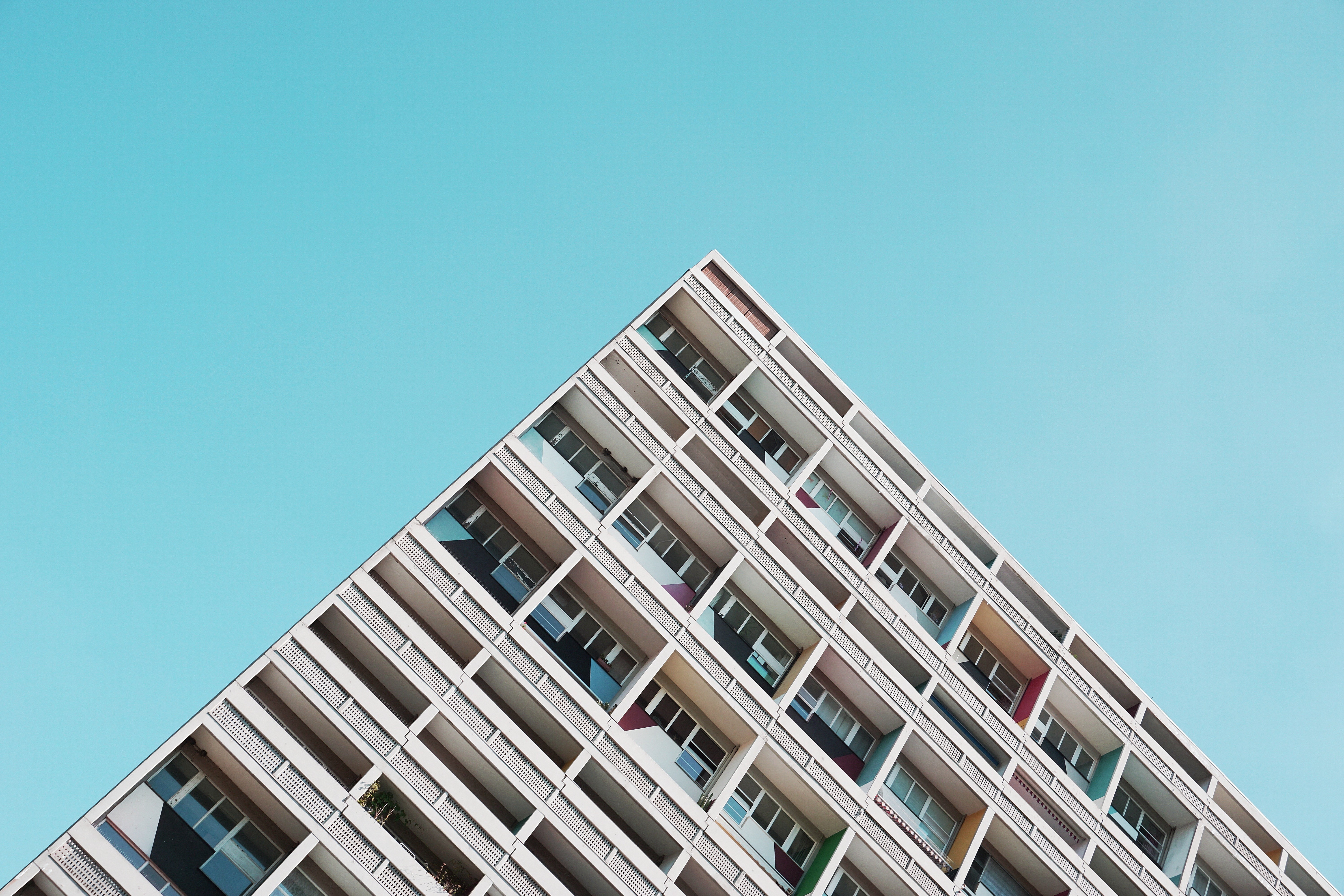 Modern apartment building facade against a clear blue sky HD Wallpaper