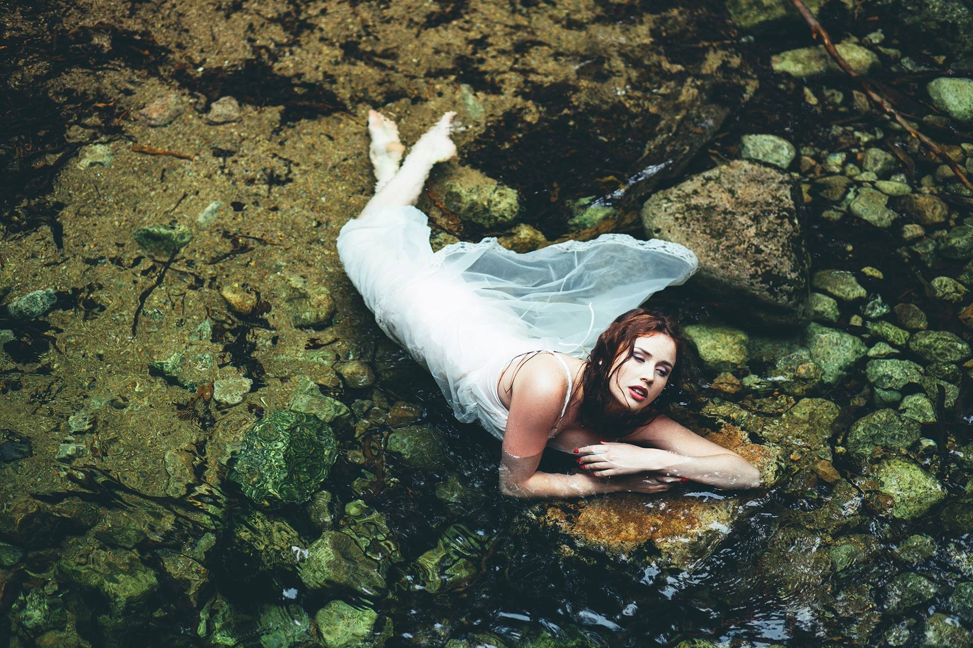 Woman in white dress lying in a rocky stream HD Wallpaper
